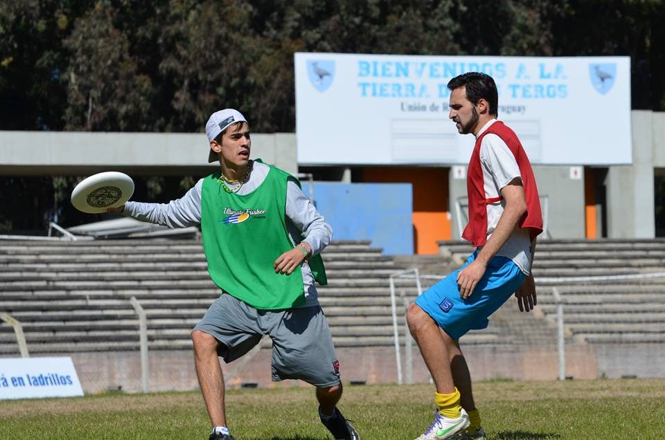 Dos jugadores de ultimate en un estadio durante el Hat Charrúa 2013, uno con pechera verde y disco en la mano